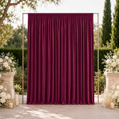Elegant burgundy wedding backdrop with floral arrangements and candles outdoors