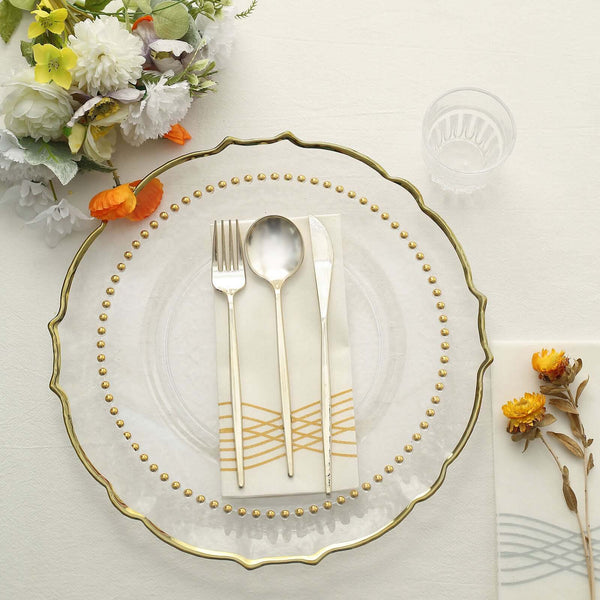 Elegant clear dinner plate with gold accents and cutlery on a table setting.