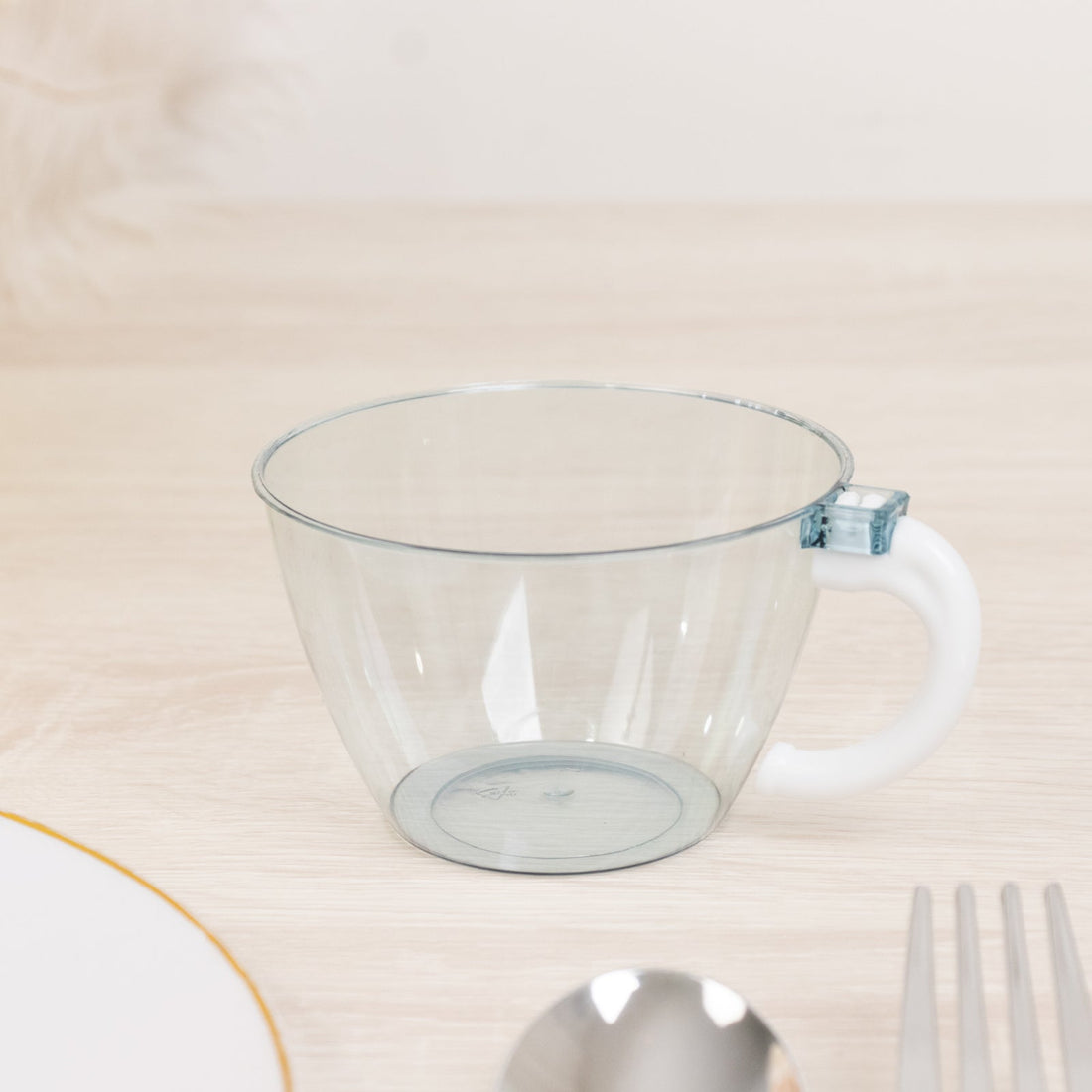 Clear plastic cup with a white handle and blue accent on a wooden surface.