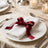 Elegant dinner table setting with white napkin and burgundy ribbon bow