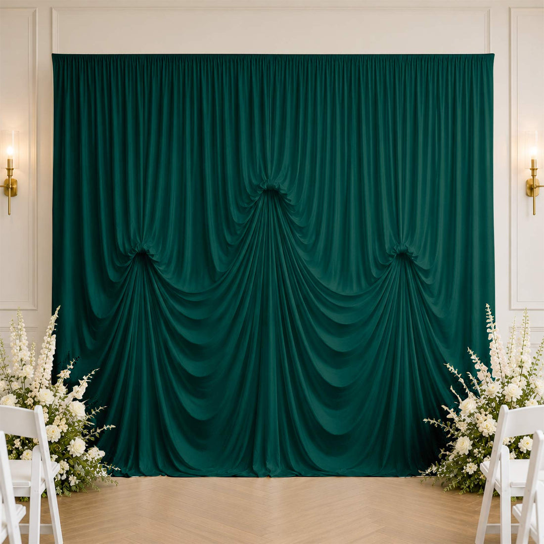 Elegant emerald green draped backdrop with floral arrangement in wedding venue