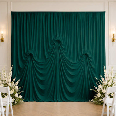 Elegant emerald green draped backdrop with floral arrangement in wedding venue