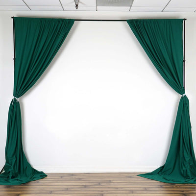Green fabric curtains draped on a backdrop stand in a studio setting.