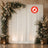 Elegant floral wedding backdrop with draped white curtain and lanterns
