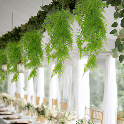 Elegant garden event table with hanging ferns and gold chairs, indoor venue