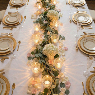 Elegant gold and white wedding table setting with floral candle centerpiece