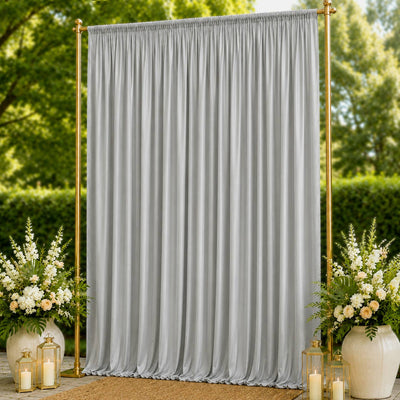 Elegant gold backdrop stand with silver curtain and floral arrangements outdoors