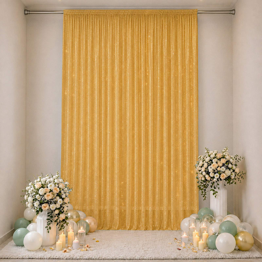 Elegant gold event backdrop with floral arrangements, candles, and pastel balloons