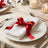 Elegant holiday table setting with white napkin and red ribbon bow