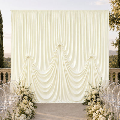 Elegant ivory draped wedding backdrop with floral aisle decor outdoors