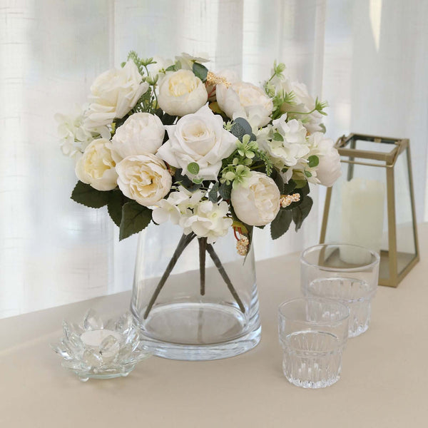 Elegant white floral arrangement in a glass vase with greenery.