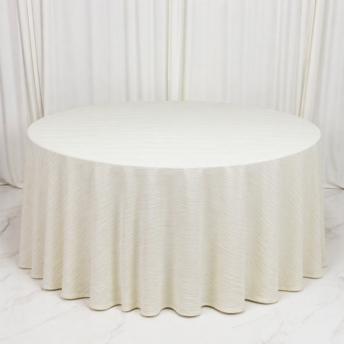 Elegant ivory round table with textured drape and white backdrop