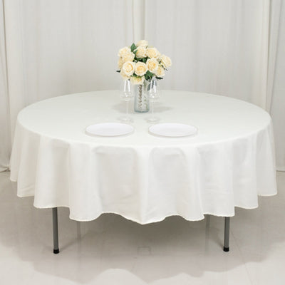 Round table set with white tablecloth and floral centerpiece.