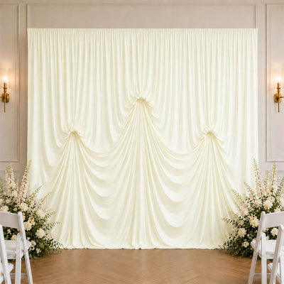Elegant ivory wedding drapery backdrop with floral arrangements and chairs