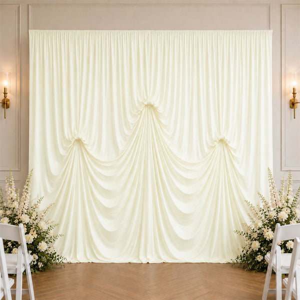 Elegant ivory wedding drapery backdrop with floral arrangements and chairs