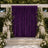 Elegant outdoor wedding backdrop with purple drapery, white flowers, and candles