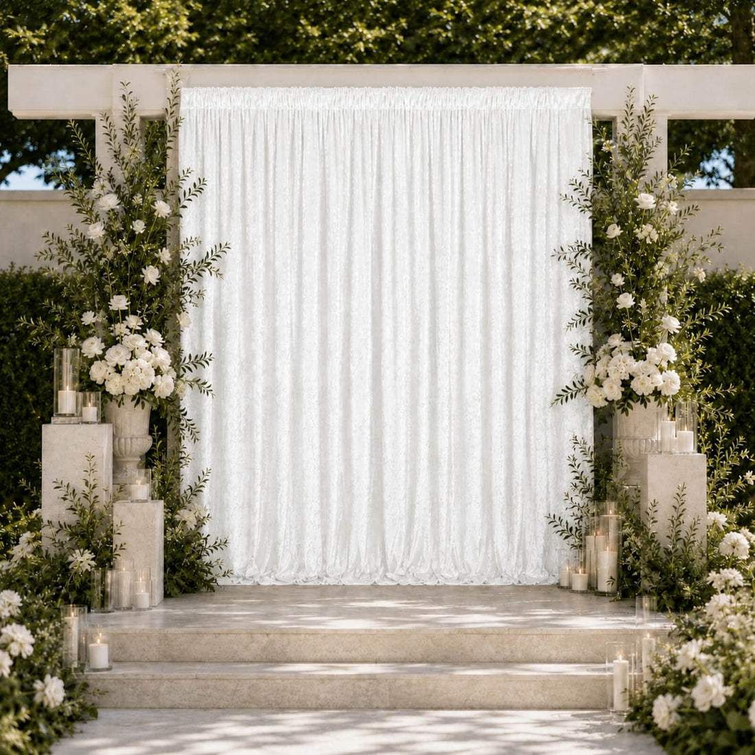 Elegant outdoor wedding ceremony arch with white drapery, flowers, and candles