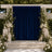 Elegant outdoor wedding ceremony backdrop with blue drape, white flowers, and candles
