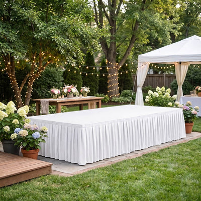 Elegant outdoor wedding setup with white table, floral decor, and string lights