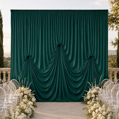 Elegant outdoor wedding stage with dark green draped backdrop and white flowers