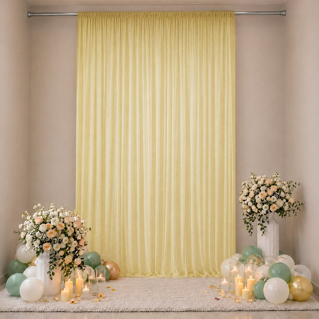 Elegant pastel party backdrop with yellow drape, flowers, candles, and balloons
