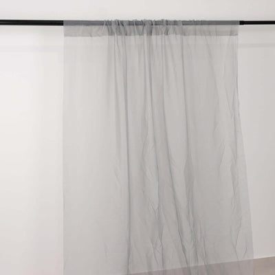 Sheer gray curtain draped on a rod against a plain backdrop