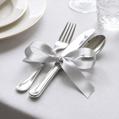 Elegant silver cutlery tied with satin ribbon on a white table setting