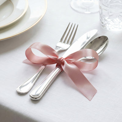 Elegant table setting with pink ribbon tied around silver cutlery and white plates