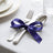 Elegant table setting with purple ribbon-tied silverware on white linen tablecloth