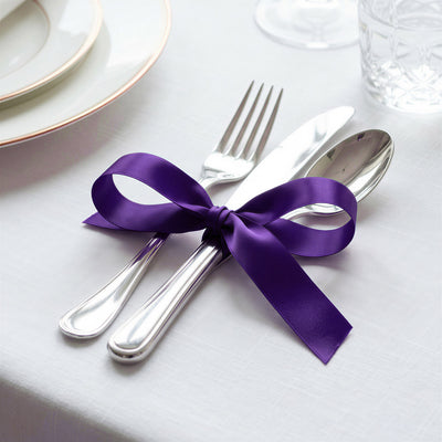 Elegant table setting with silver cutlery tied with a purple ribbon