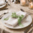 Elegant table setting with white napkin and green ribbon on dinner plate