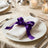 Elegant table setting with white napkin and purple ribbon bow on plate
