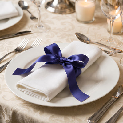 Elegant table setting with white napkin and purple ribbon on dinner plate