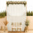 Elegant wedding backdrop with white drapes, gold chairs, and floral greenery arrangement