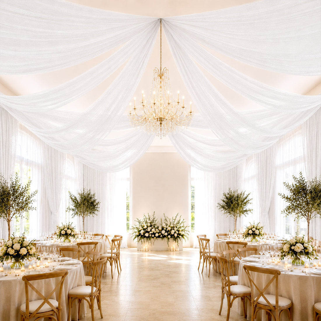 Elegant wedding reception with draped white ceiling, chandelier, and floral tables