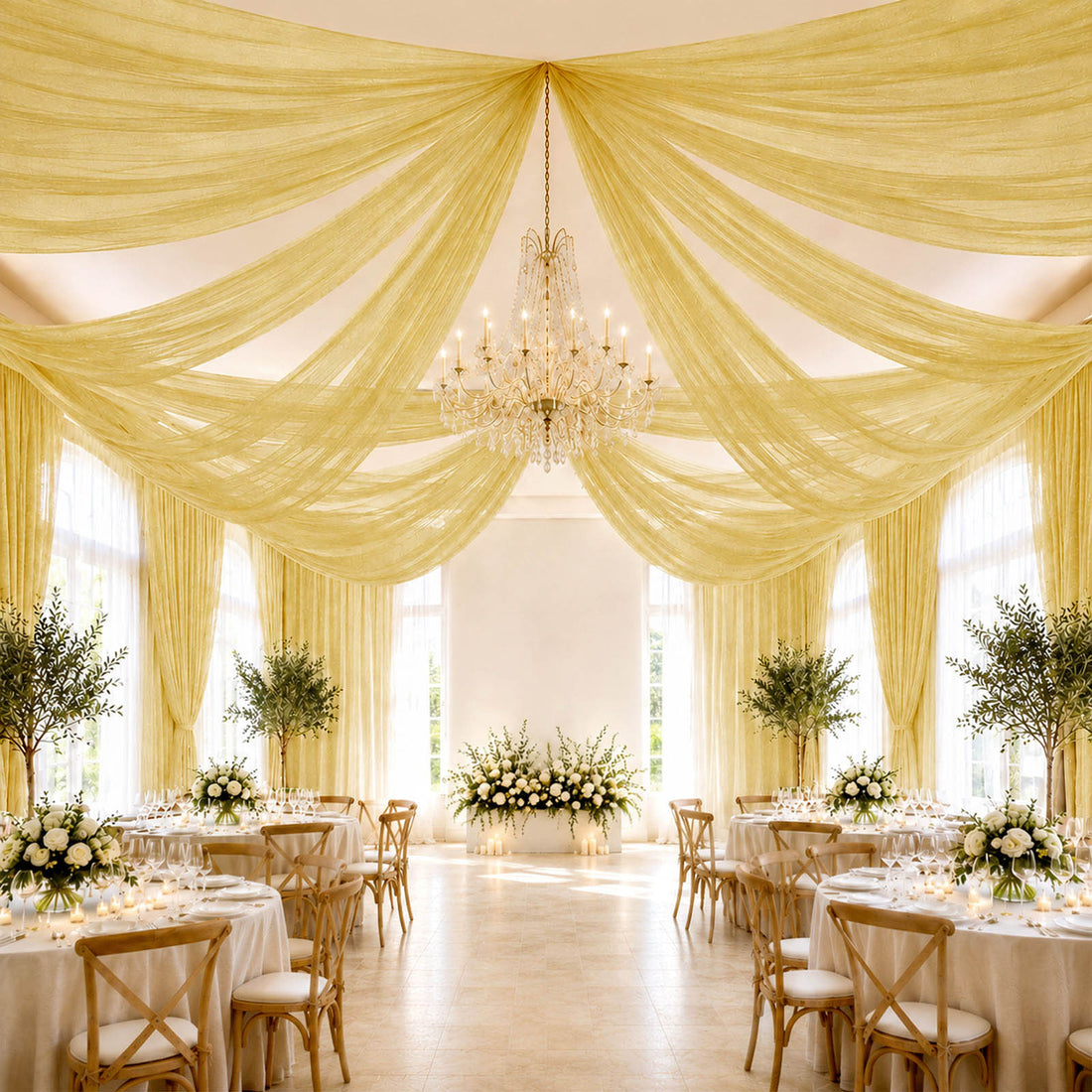 Elegant wedding reception with gold draped ceiling, chandelier, and floral tables