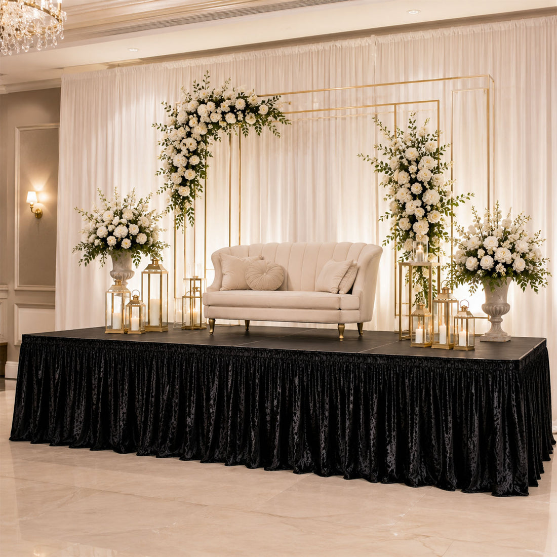 Elegant wedding stage with cream sofa, white florals, gold frames, and candles