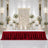 Elegant wedding stage with floral backdrop, gold accents, and red velvet table skirt