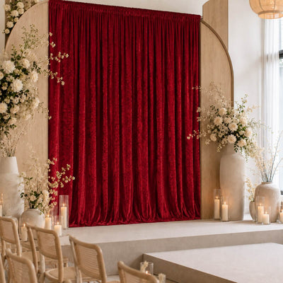 Elegant wedding stage with red velvet curtain, floral arrangements, and candles