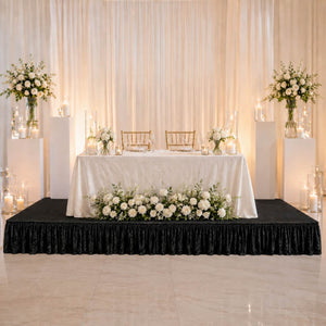 Elegant wedding sweetheart table with white roses, candles, and gold chairs