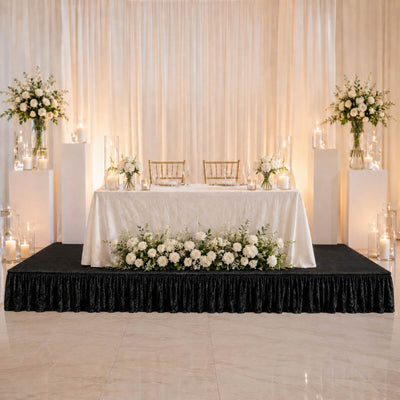 Elegant wedding sweetheart table with white roses, candles, and gold chairs