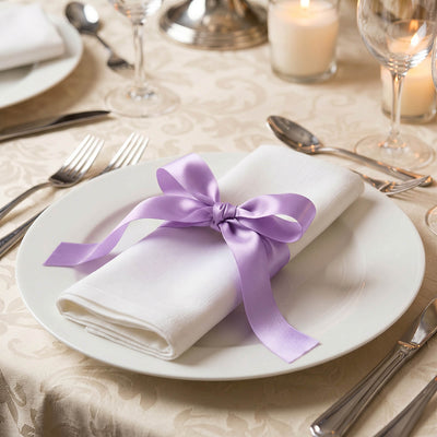 Elegant wedding table setting with white napkin and lavender ribbon bow