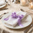 Elegant wedding table setting with white napkin and lavender ribbon bow
