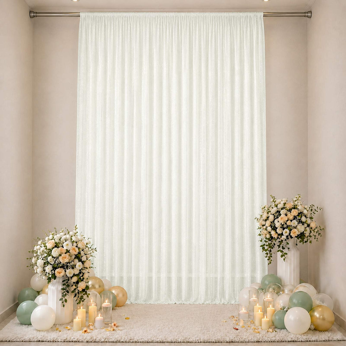 Elegant white curtain backdrop with floral arrangements, balloons, and candles