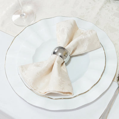 Elegant white dinner plate with folded cream napkin and silver napkin ring