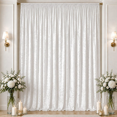 Elegant white draped curtain backdrop with floral arrangements and candles