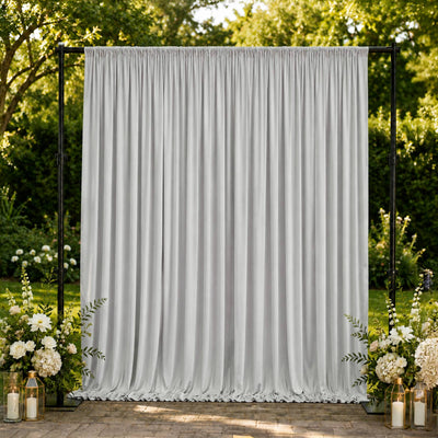 Elegant white event curtain backdrop with floral arrangements and lanterns outdoors
