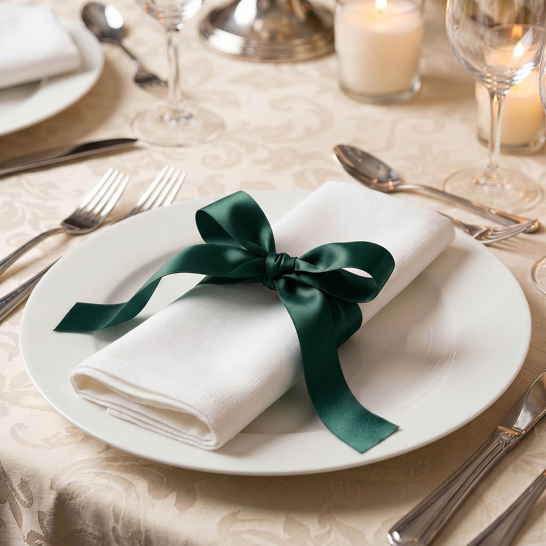 Elegant white napkin with green ribbon on formal dining table setting
