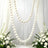 Elegant white wedding backdrop with pearl garland and floral arrangements
