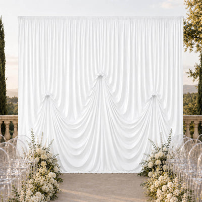 Elegant white wedding draped backdrop with floral aisle decor outdoors